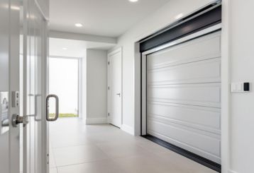 Bright, modern garage interior in Magna, Utah, featuring a freshly painted white garage door with recessed panels and stylish black hardware.