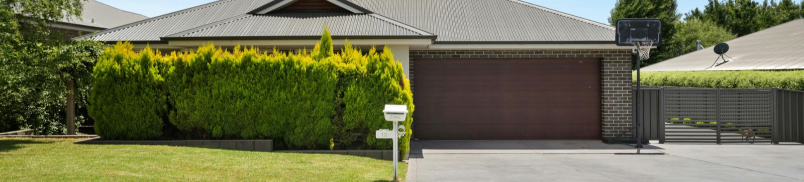 Front view of a contemporary house in Magna featuring a sleek double garage door, manicured lawn, and clear blue sky.