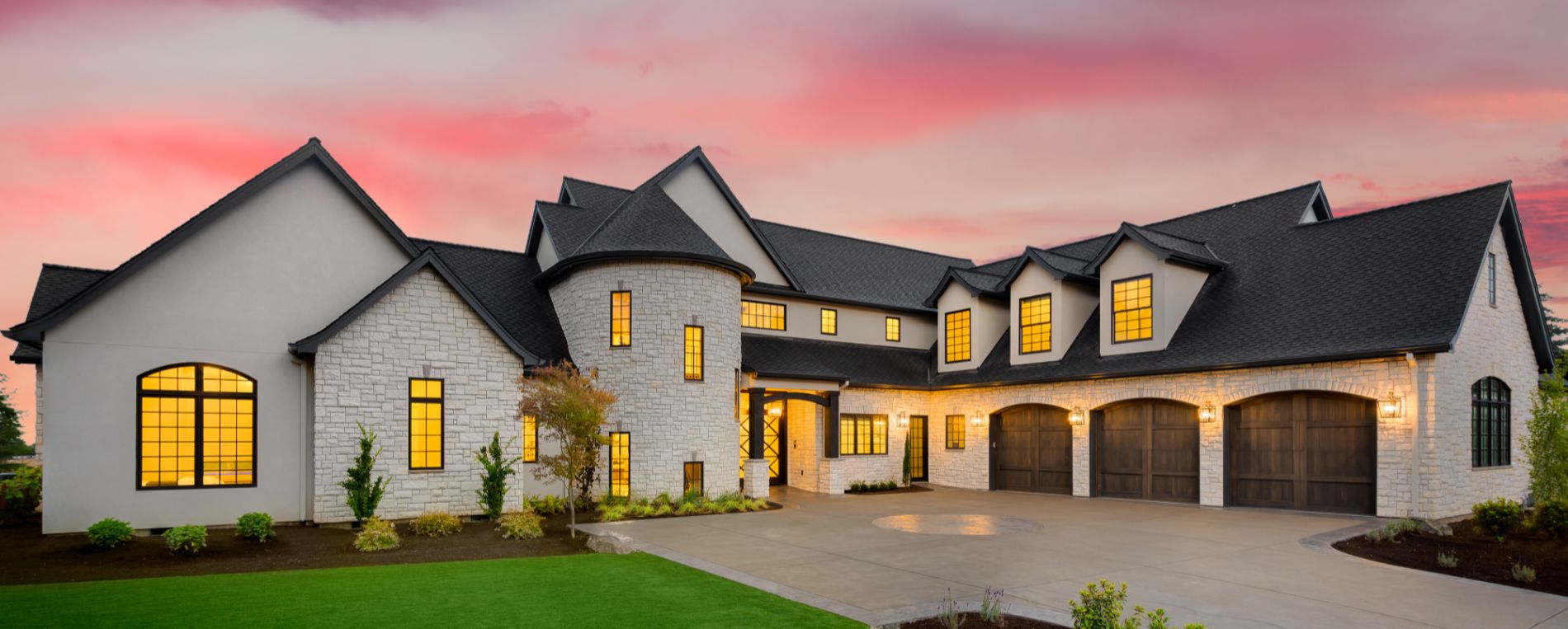 Elegant two-story house with stone exterior, black roof, and three wooden garage doors at sunset, showcasing premium garage door installation by Magna Garage Door Repair.
