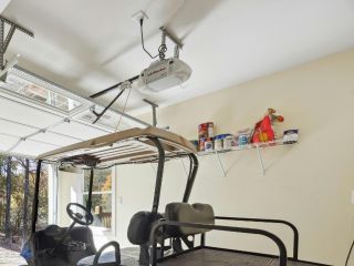 Garage Door Opener with Battery Backup – Magna Home Spacious Magna garage interior with an automatic overhead door opener equipped with battery backup, a blue golf cart, and organized wall shelves.
